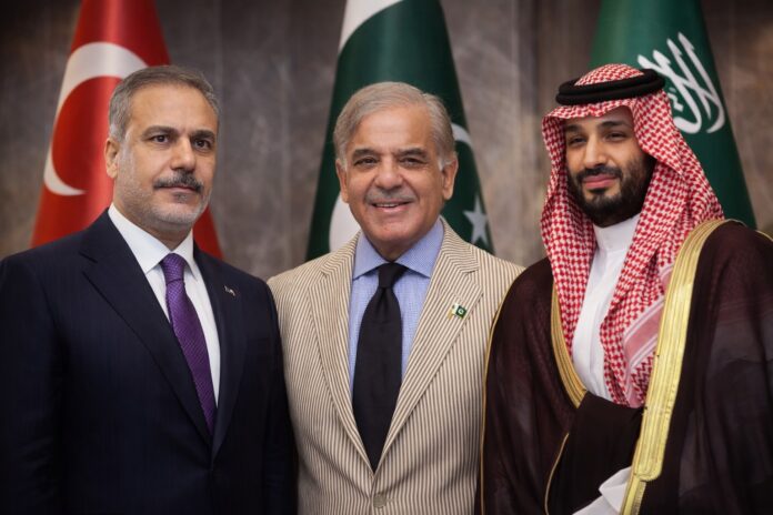 Turkish Foreign Minister Hakan Fidan standing alongside Pakistan’s Prime Minister Shehbaz Sharif and Saudi Crown Prince Mohammed bin Salman